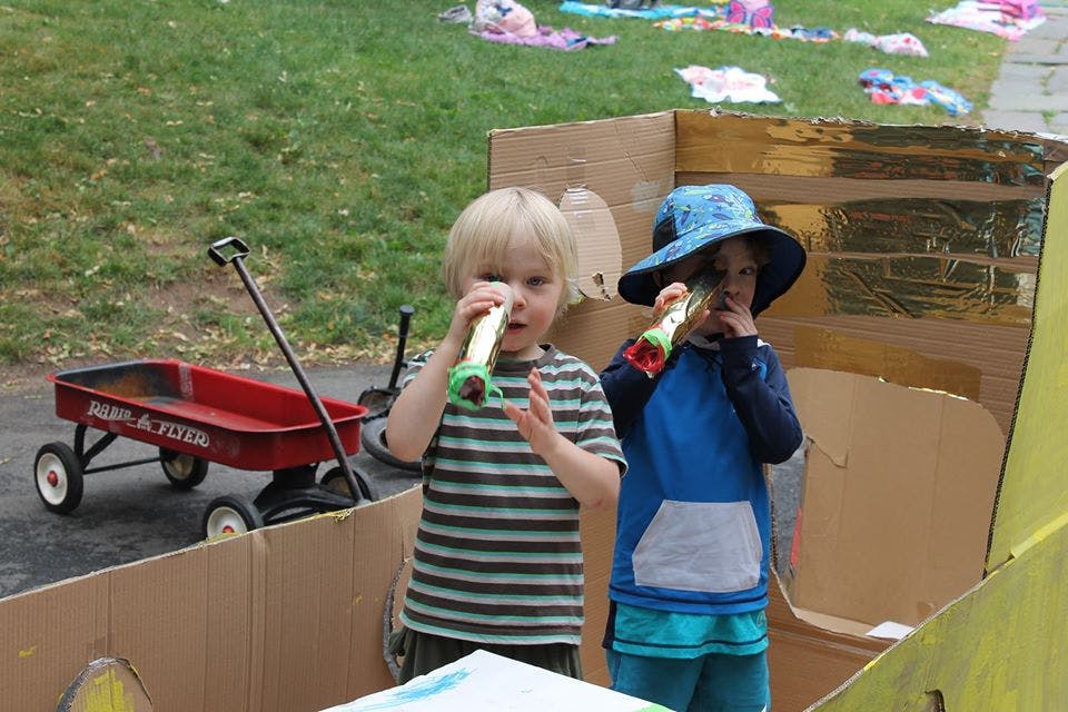 Two children playing with cardboard tubes