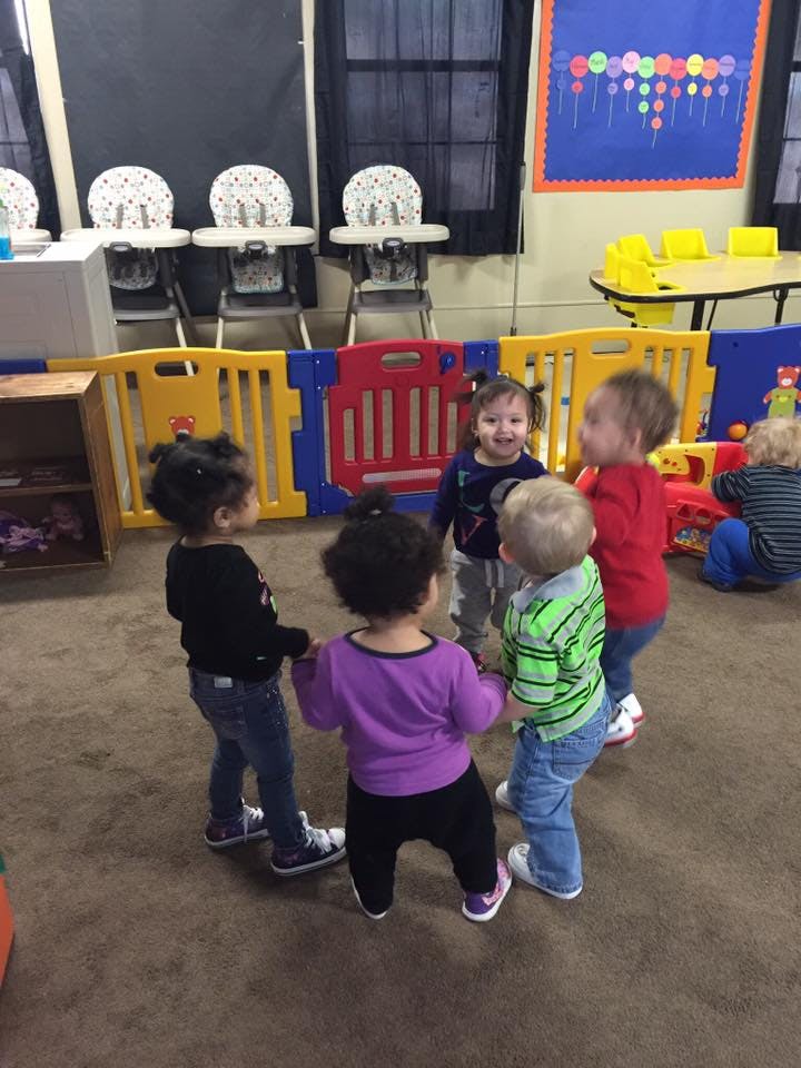 Group of children standing in a circle in a classroom