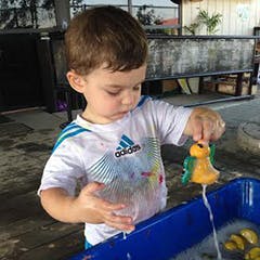 Child playing with a toy in a water bin