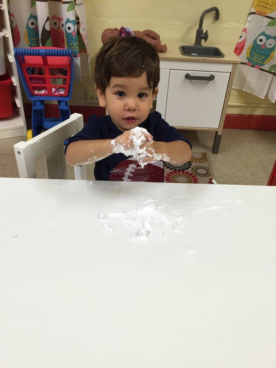 Child with white substance on hands and table