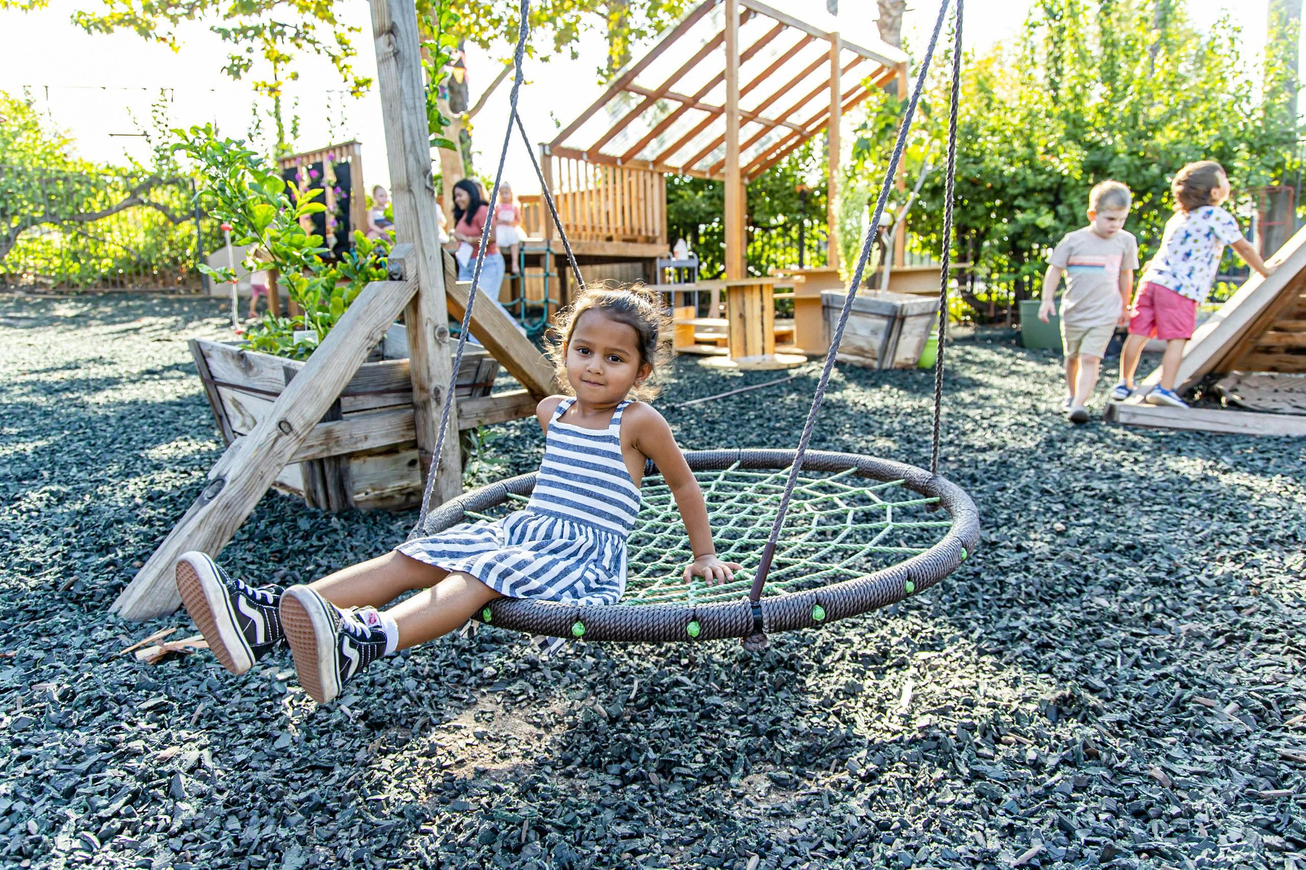 Child sitting on a round swing at a playground