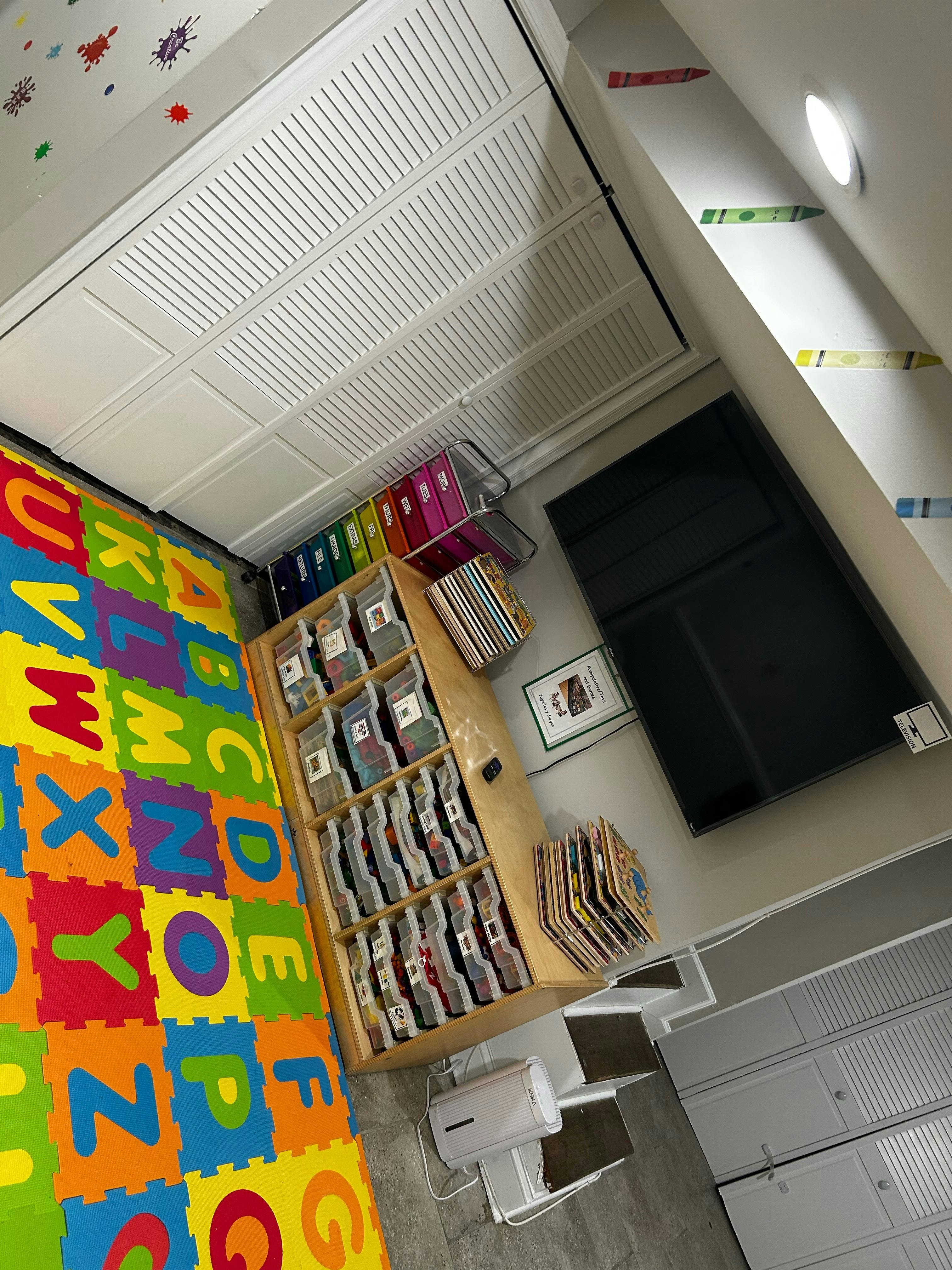 Colorful alphabet playmat next to a wooden shelf with books