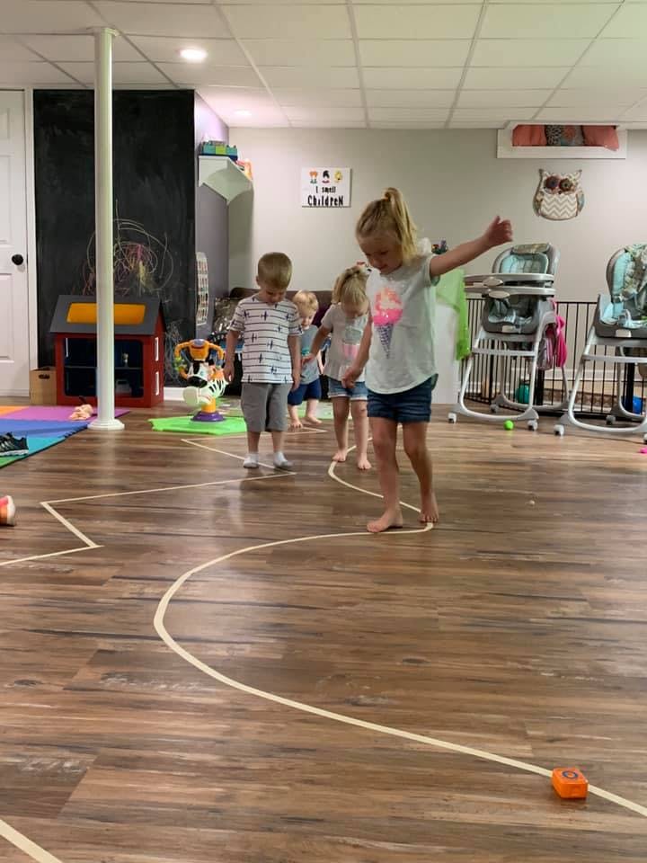 Children playing on a wooden floor with taped lines