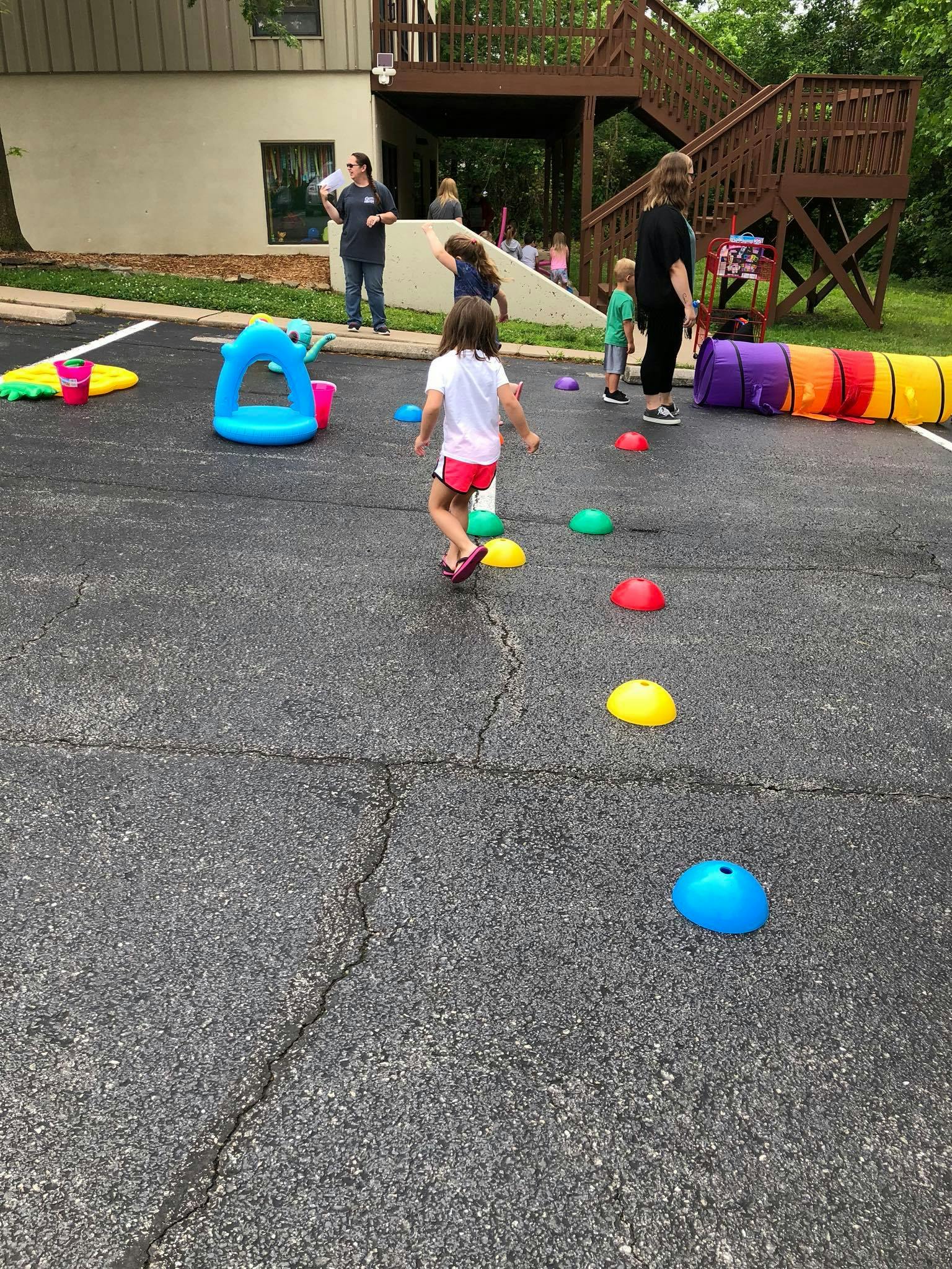 Child running on asphalt with colorful markers and inflatable play items