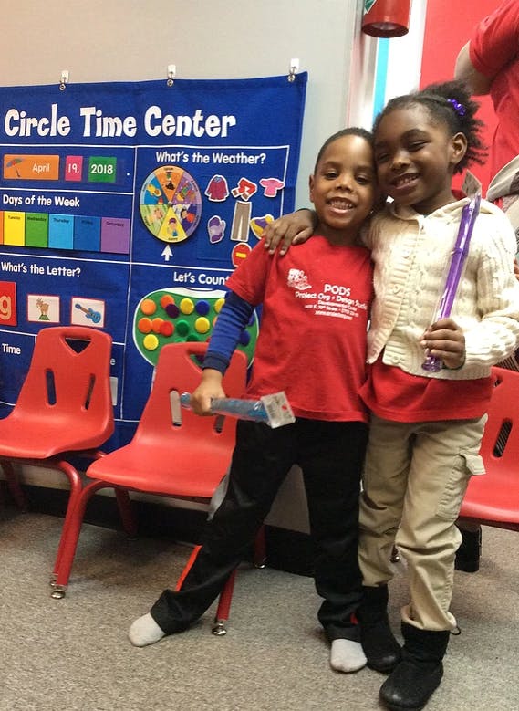 Two children standing in front of a "Circle Time Center" chart