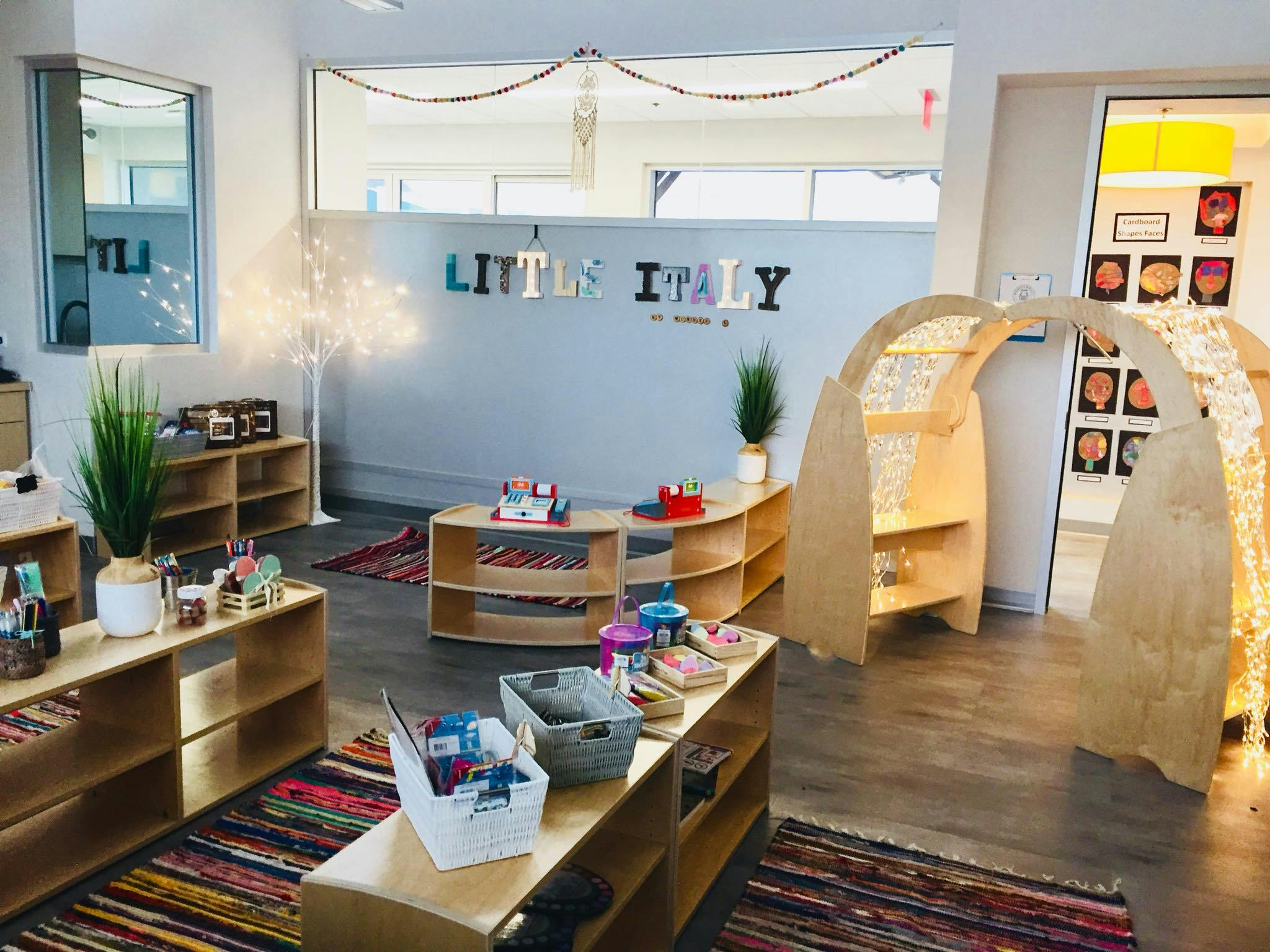 Classroom with wooden shelves, rugs, and a play arch