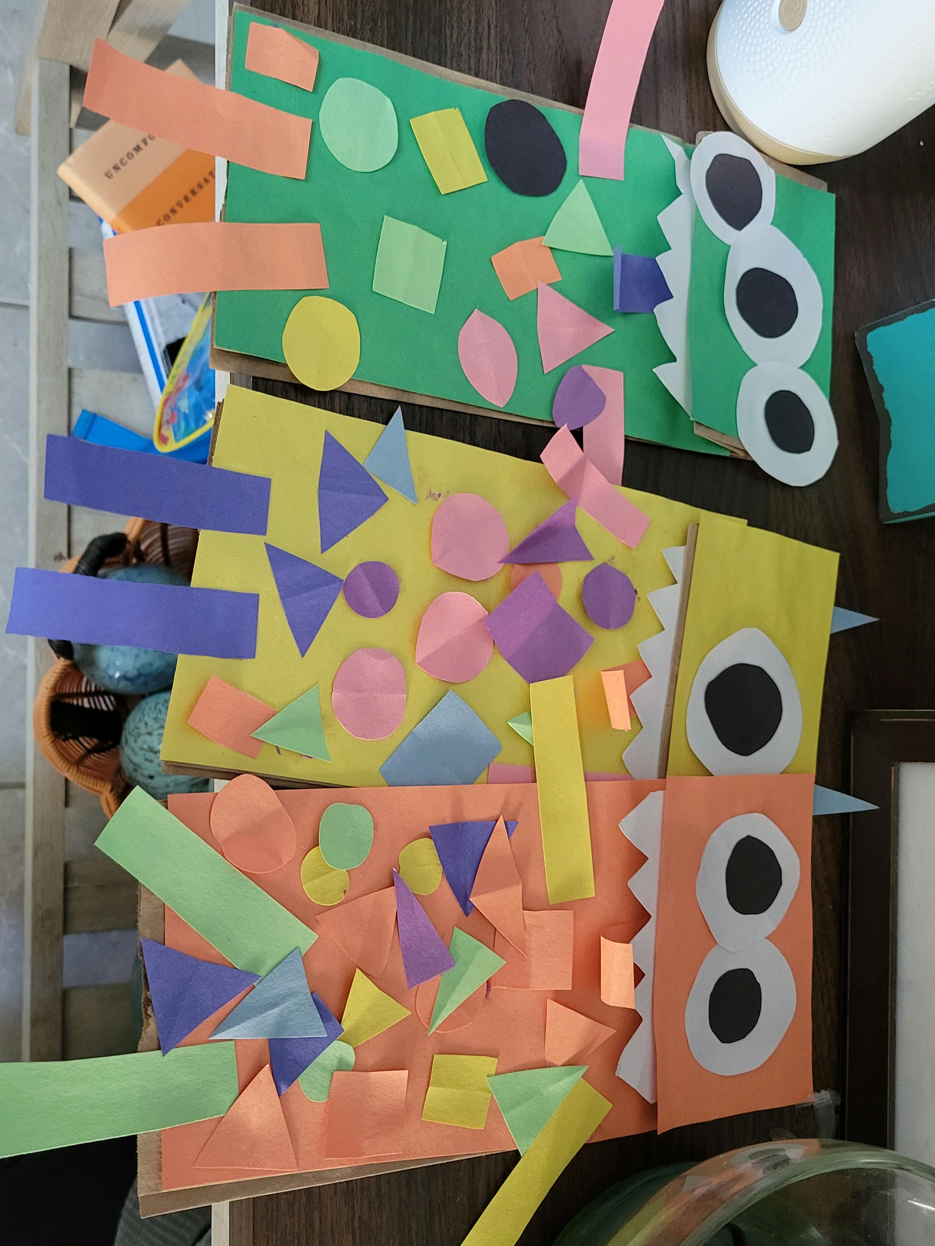 Three colorful paper craft monsters with geometric shapes