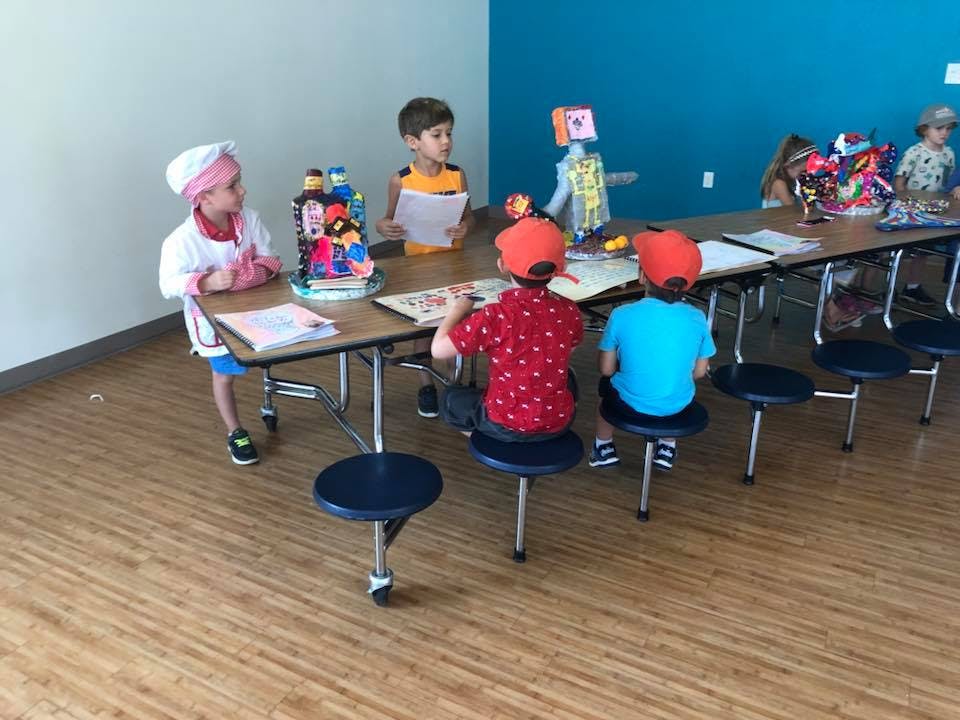 Children sitting at a long table in a classroom