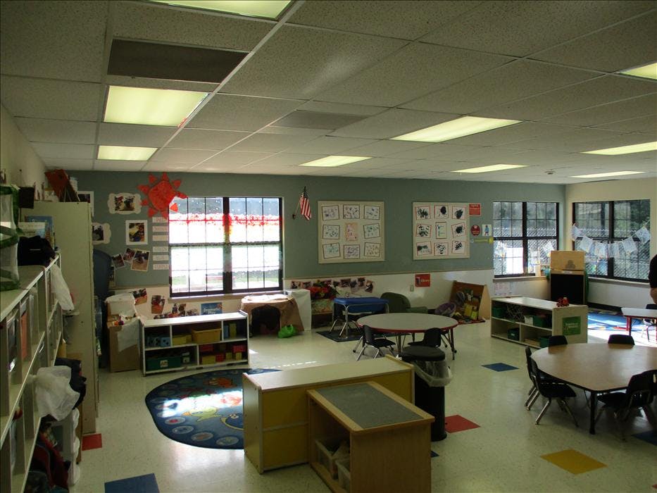 Empty classroom with tables, chairs, and shelves