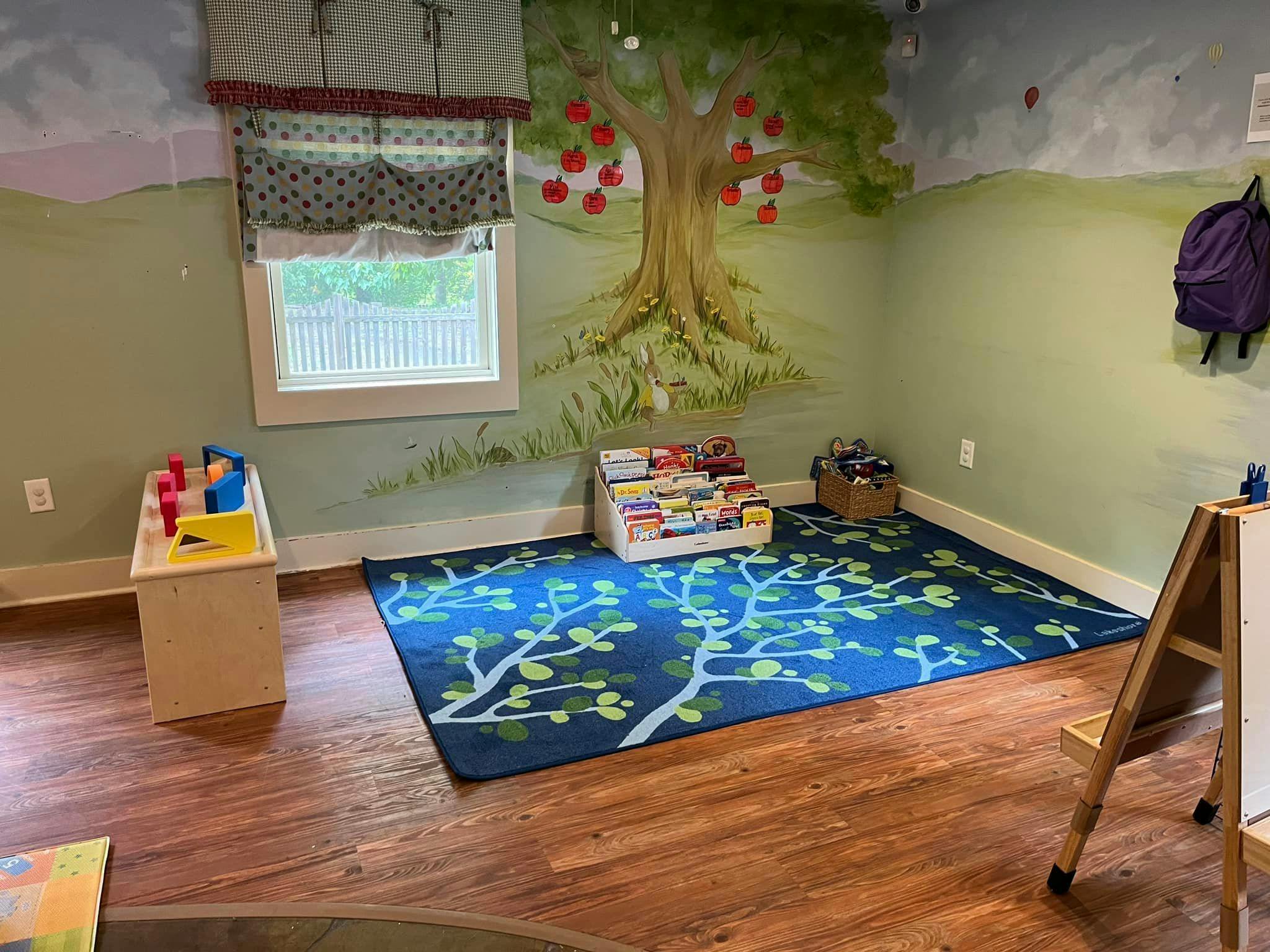 Playroom with a tree mural, blue rug, and children's books