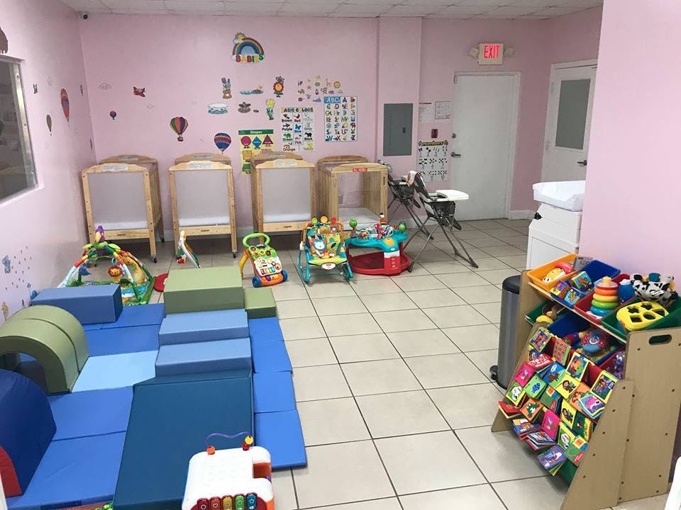 Daycare room with soft play equipment, cribs, and toys