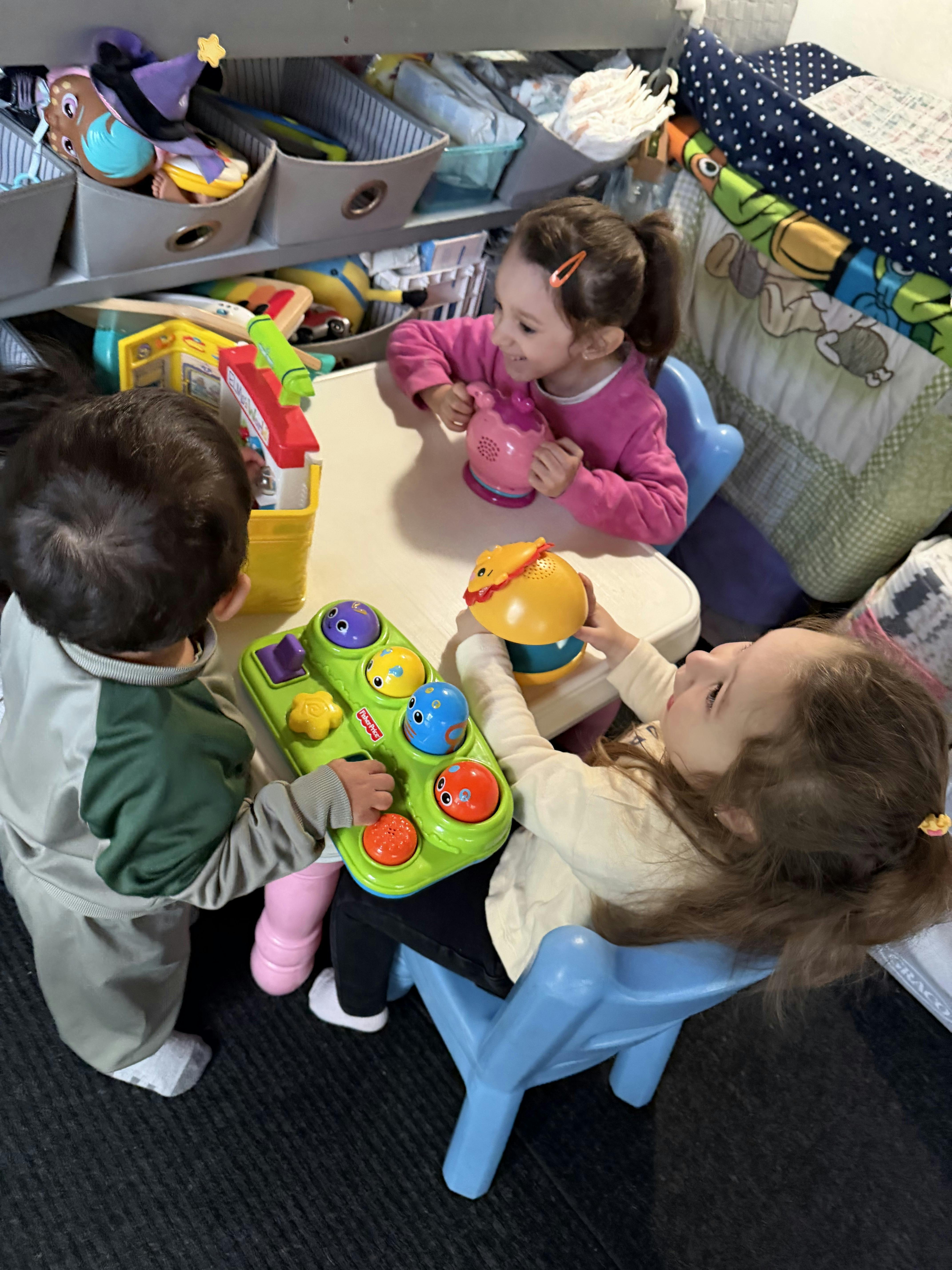 Three children playing with toys at a small table