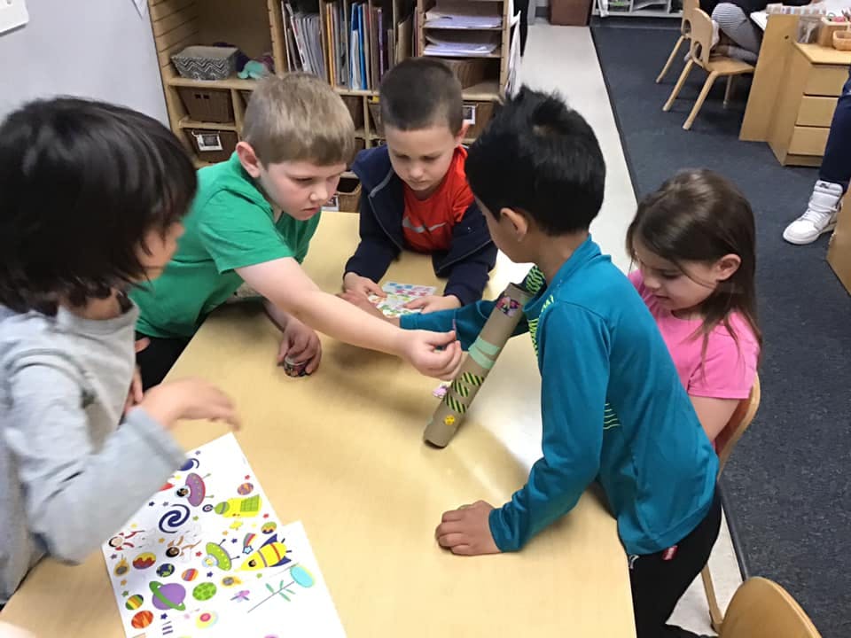 Children gathered around a table, interacting with an object