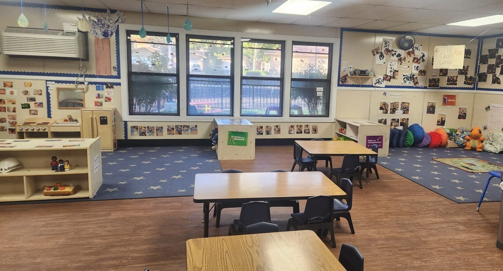 Classroom with tables, chairs, play kitchen, and colorful bean bags