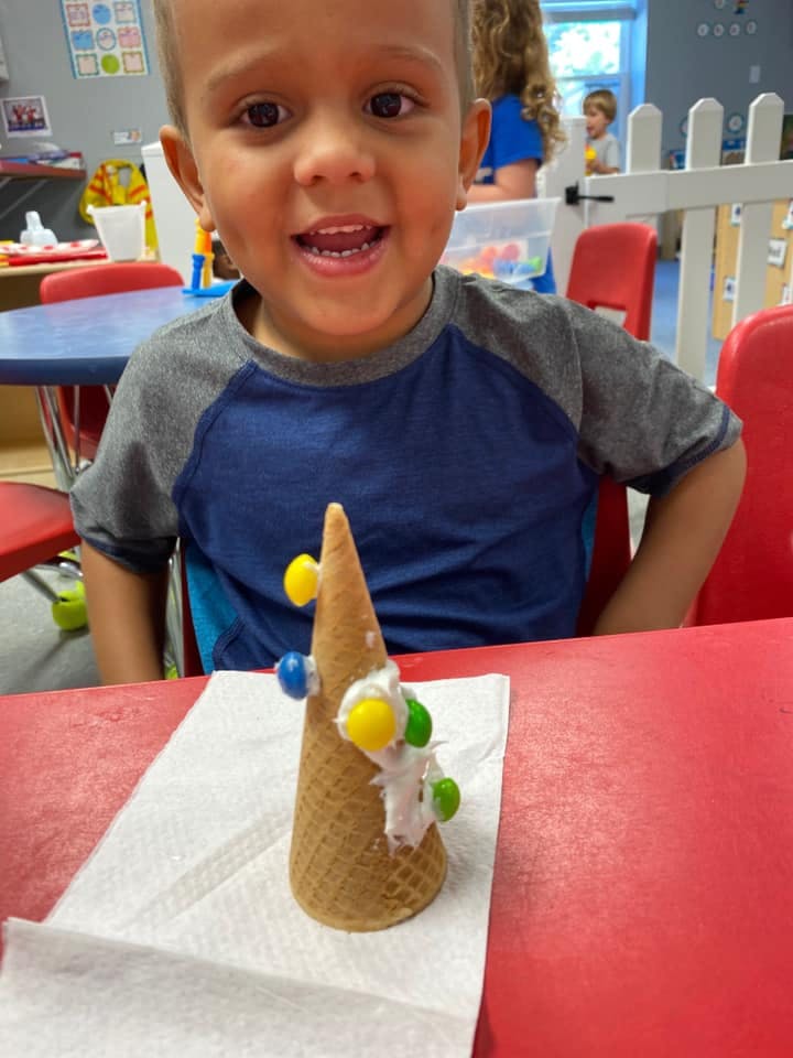Child looking at a decorated ice cream cone on a table