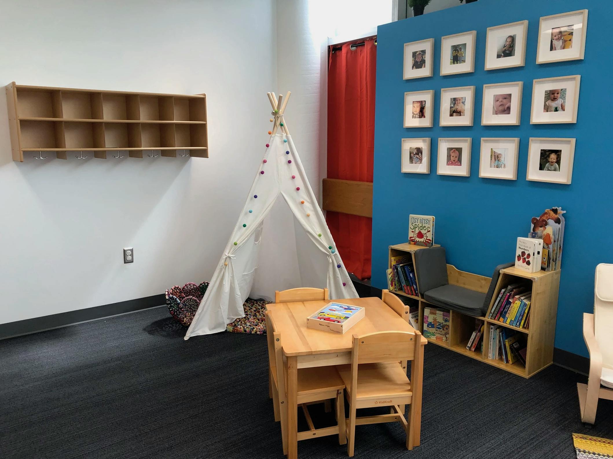 Children's play area with a teepee, small table and chairs, and bookshelves
