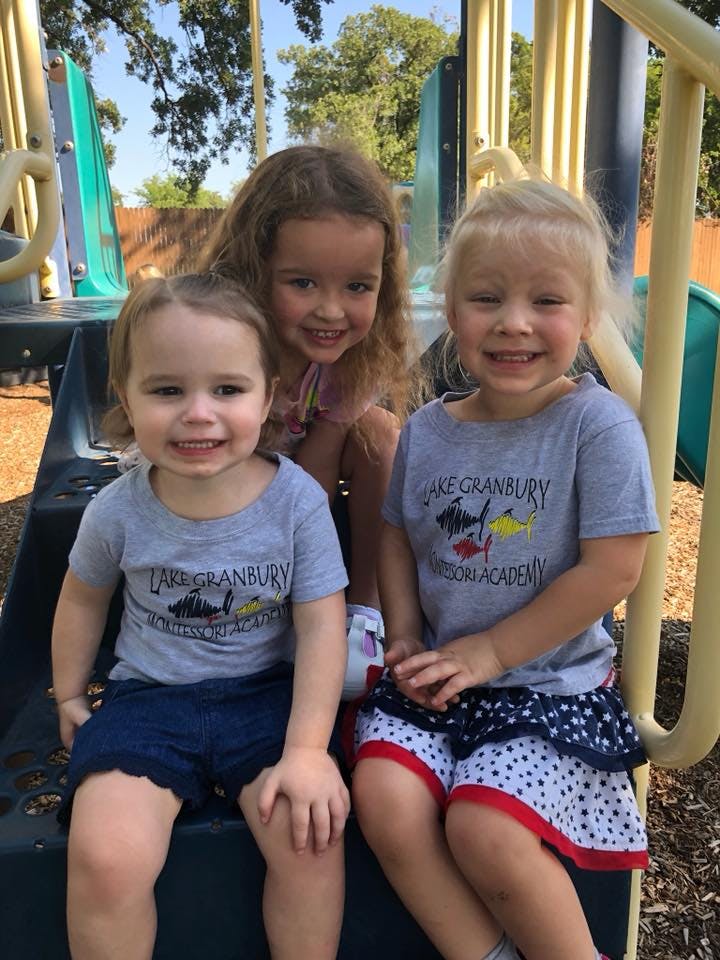 Three children sitting on playground equipment