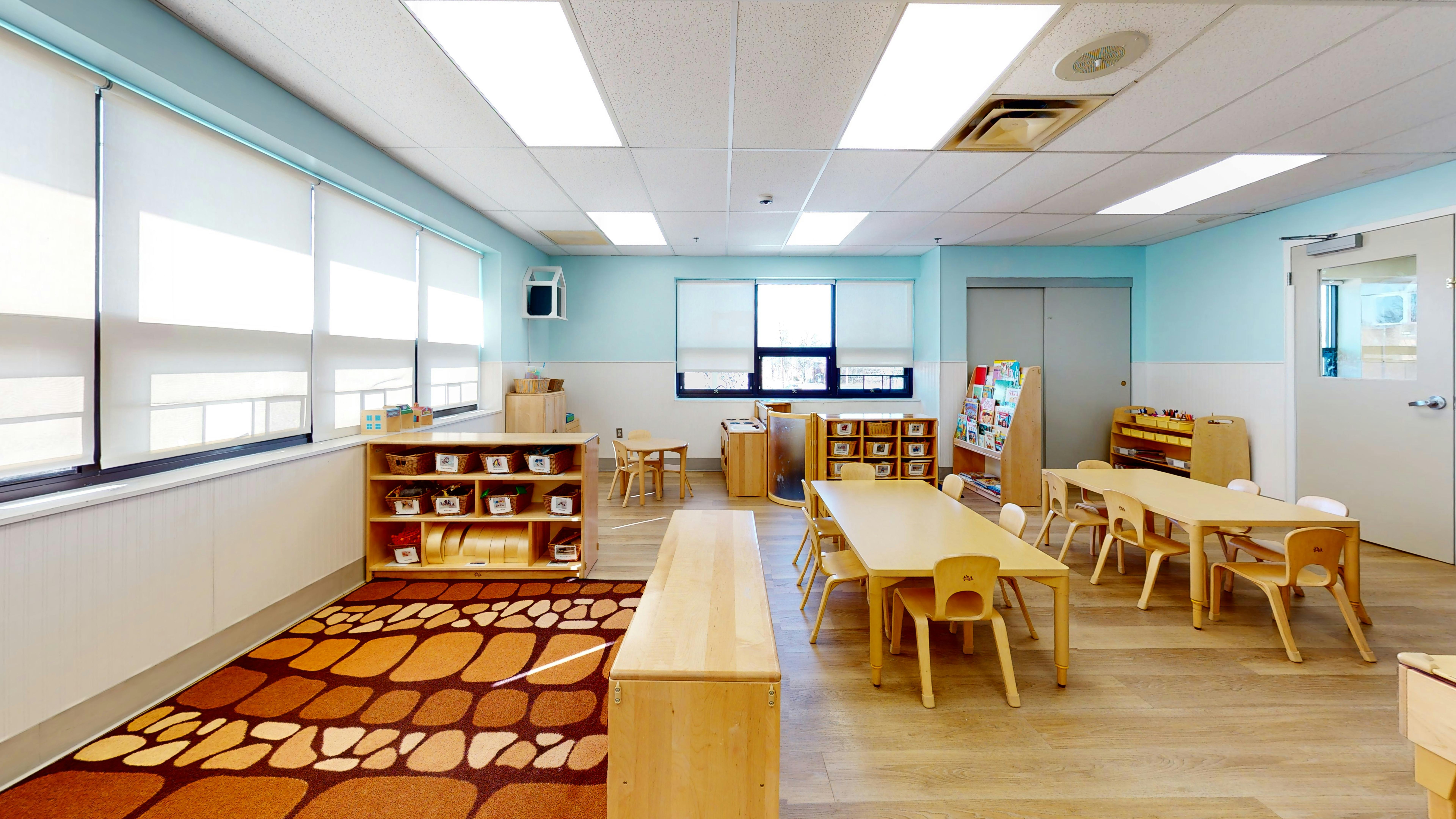 Classroom with small tables and chairs, and a patterned rug