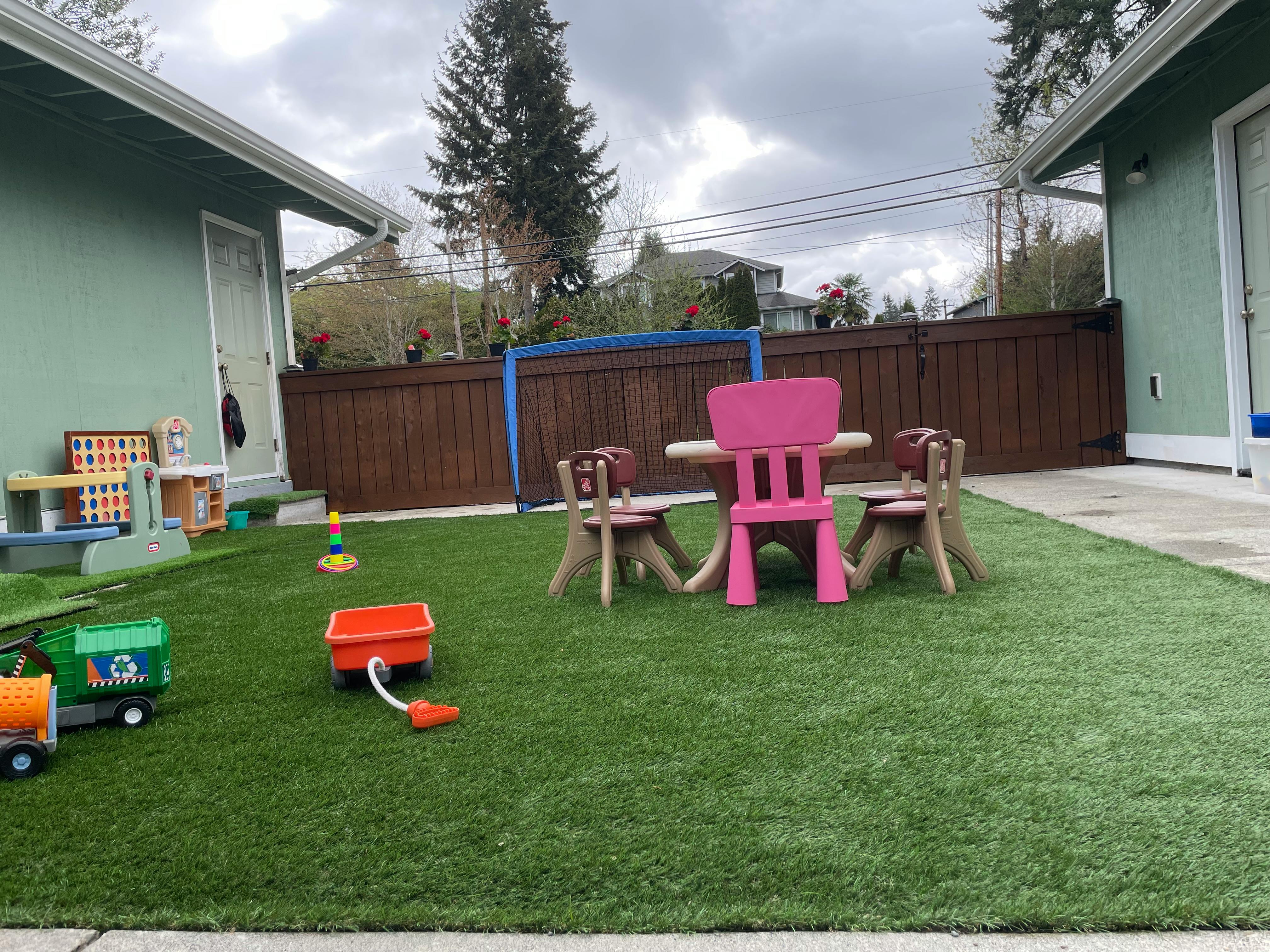 Outdoor play area with artificial grass, small table and chairs, and toys