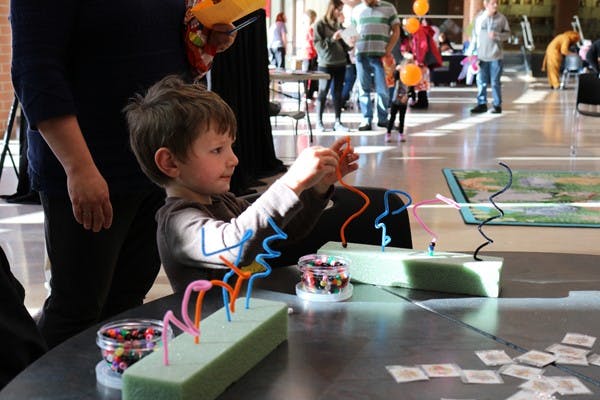 Child playing with pipe cleaners and foam blocks at a table