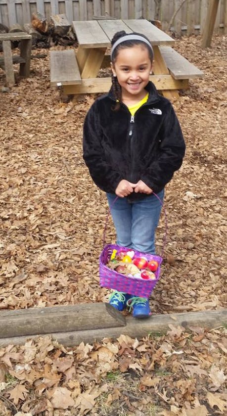 Child holding a purple basket filled with items