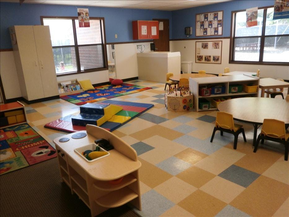 Classroom with play mats, small tables and chairs, and a toy kitchen