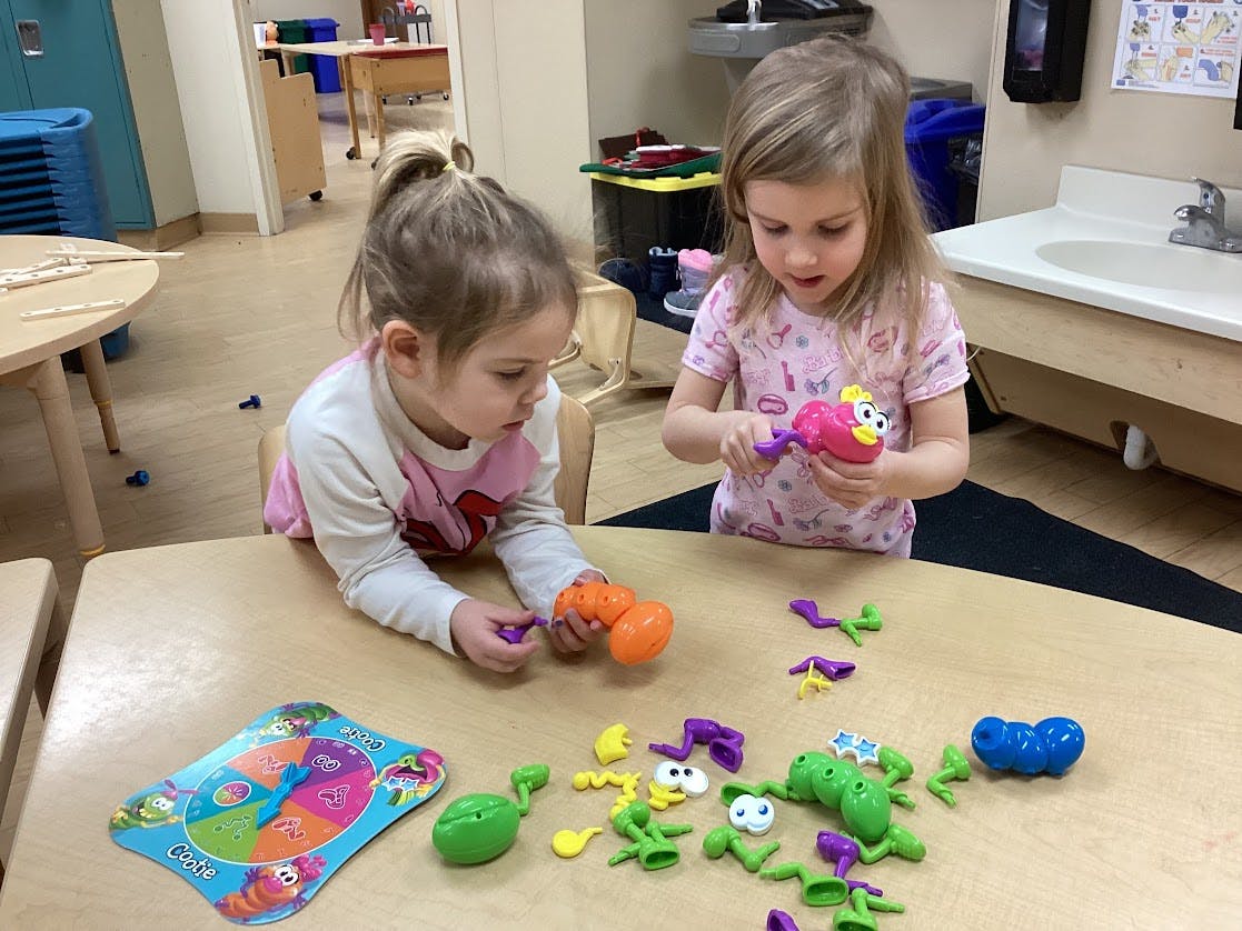 Two children playing with colorful insect-shaped toys at a table