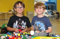 Two children standing behind a table with building blocks