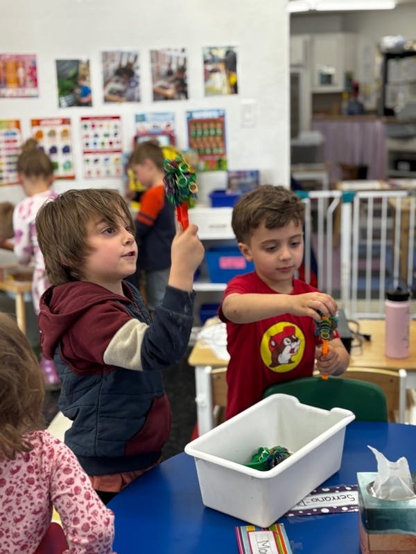 Two children playing with toys at a table in a classroom