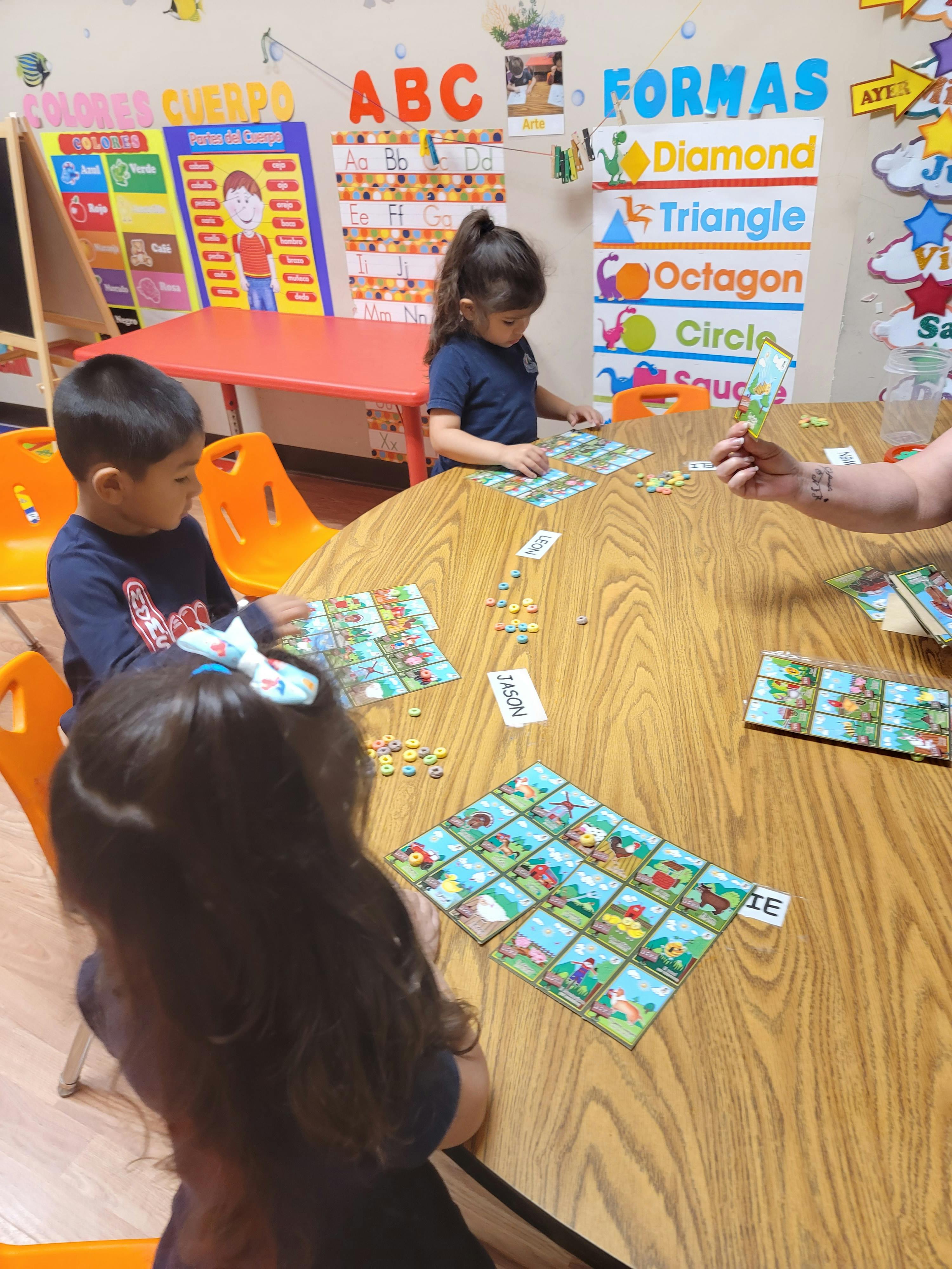 Three children playing a board game at a table in a classroom