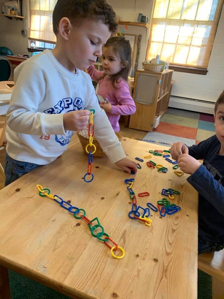 Child playing with colorful linking toys at a table