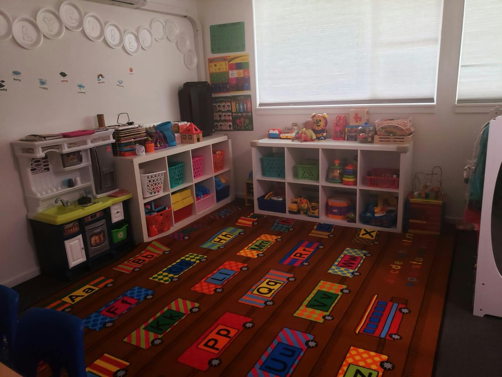 Playroom with toy kitchen, storage shelves, and colorful rug