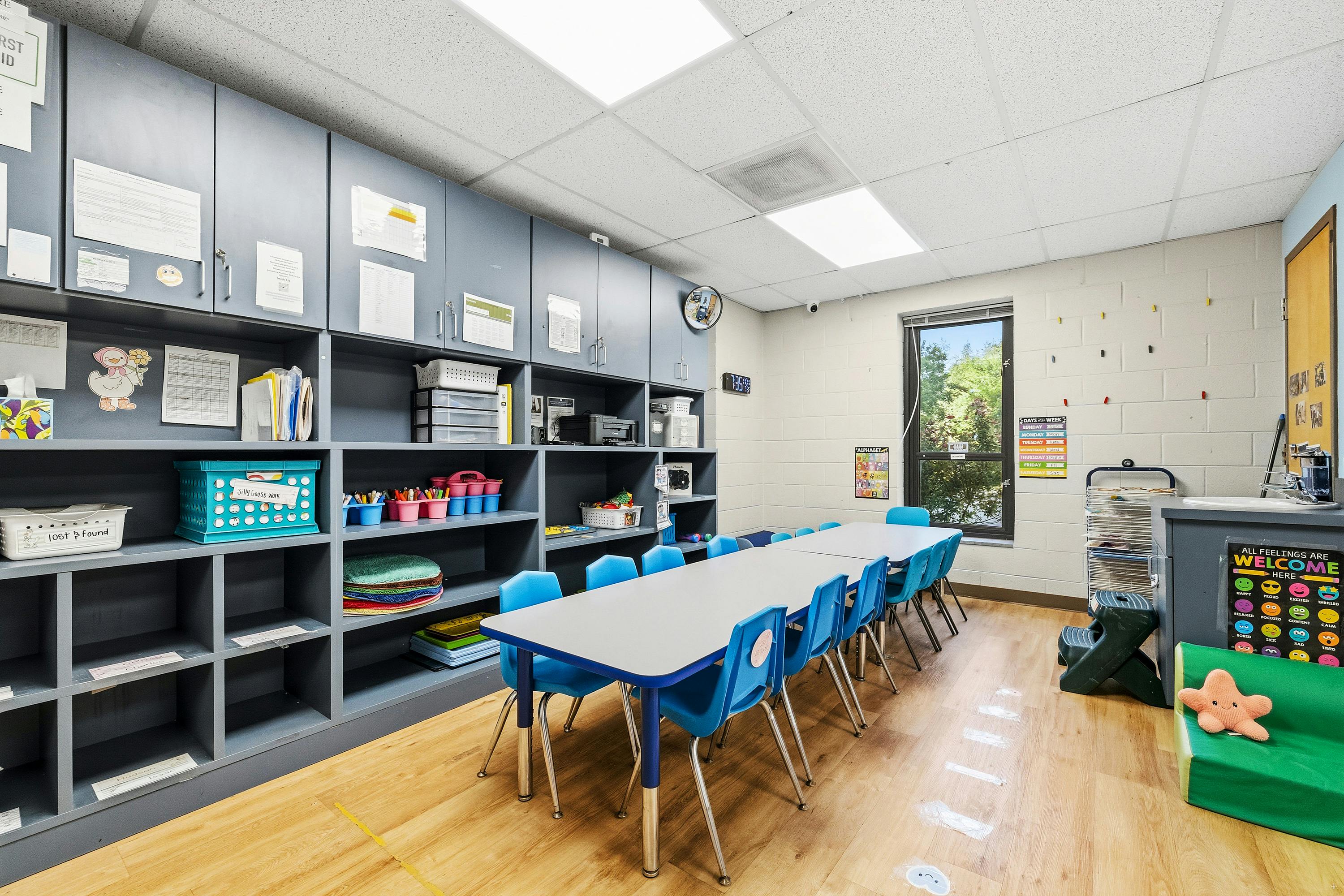 Classroom with blue tables and chairs along shelving units