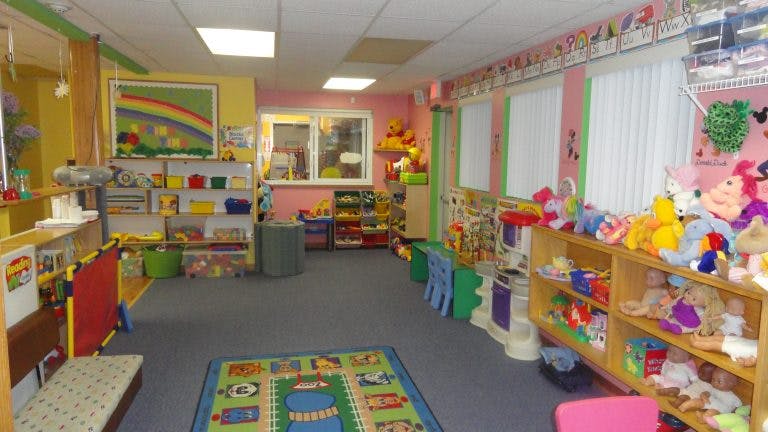 Playroom with toys on shelves and a colorful rug on the floor