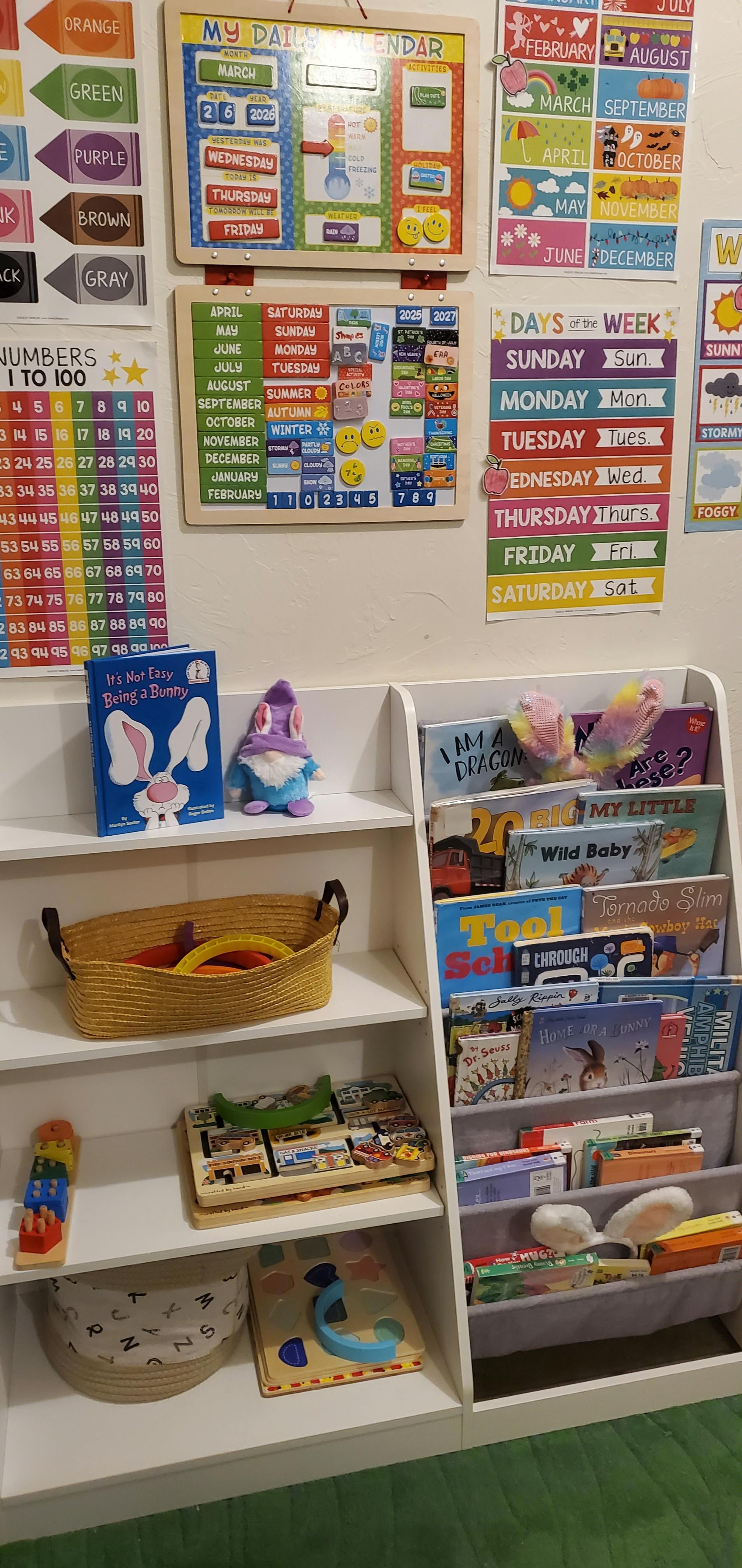 Children's learning charts for days, months, and numbers next to a bookshelf with toys and books
