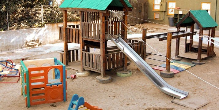 Playground with wooden structure, slide, and plastic playhouse