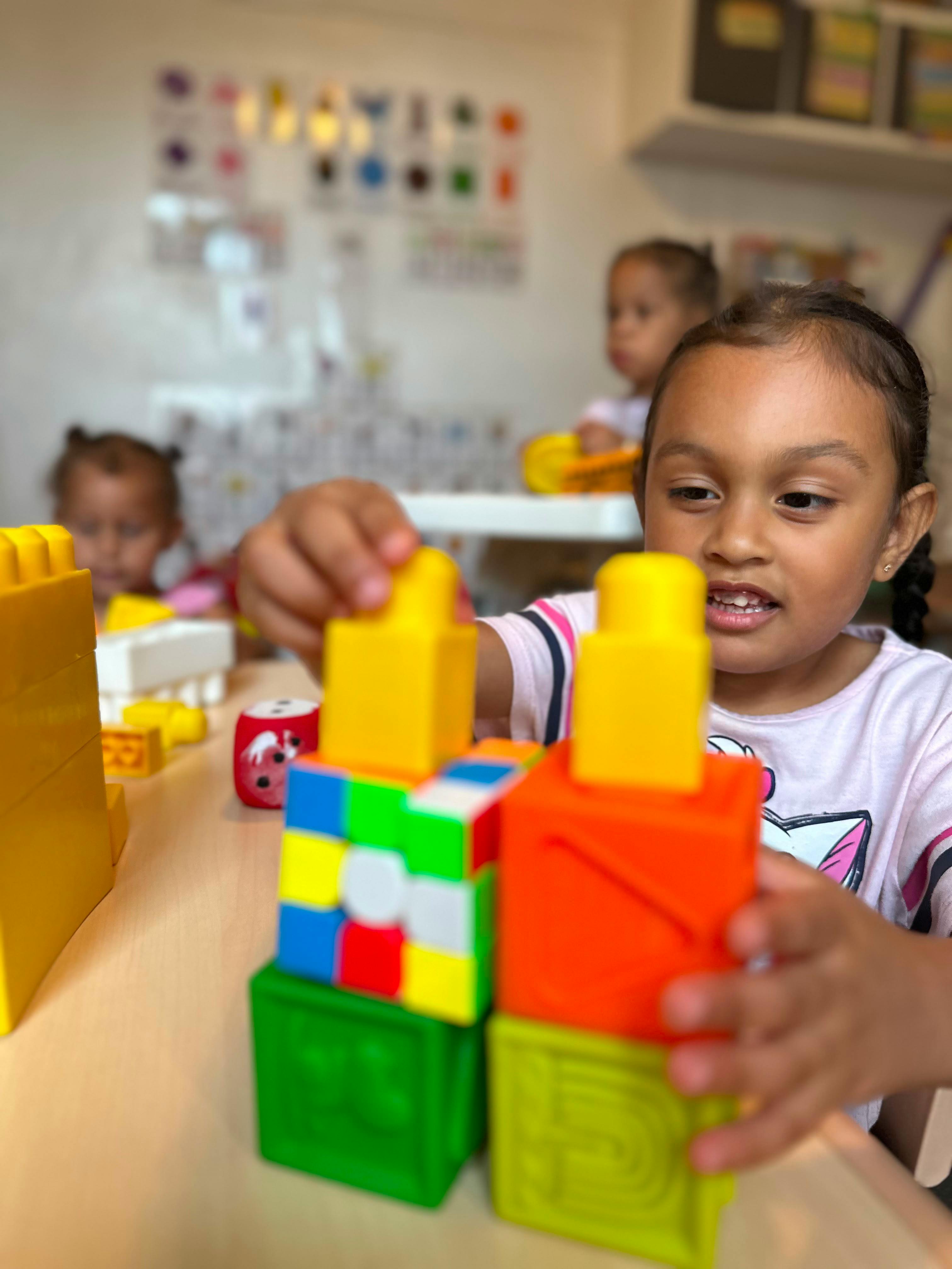 Child building a tower with colorful plastic blocks in a classroom