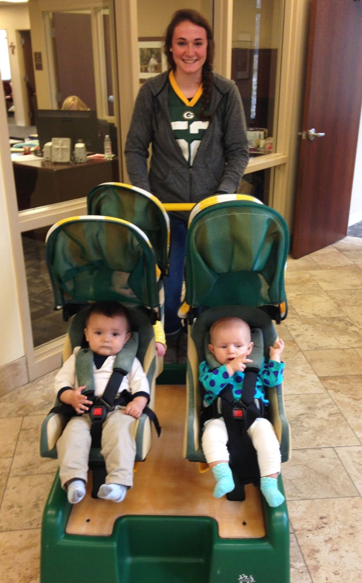 Person pushing two babies in a multi-seat stroller