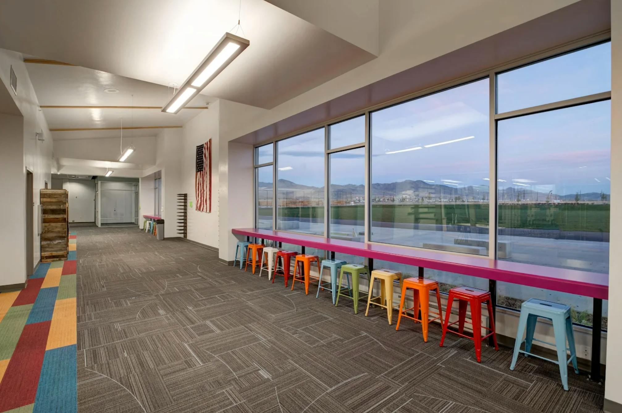 Hallway with colorful stools along a window overlooking a landscape