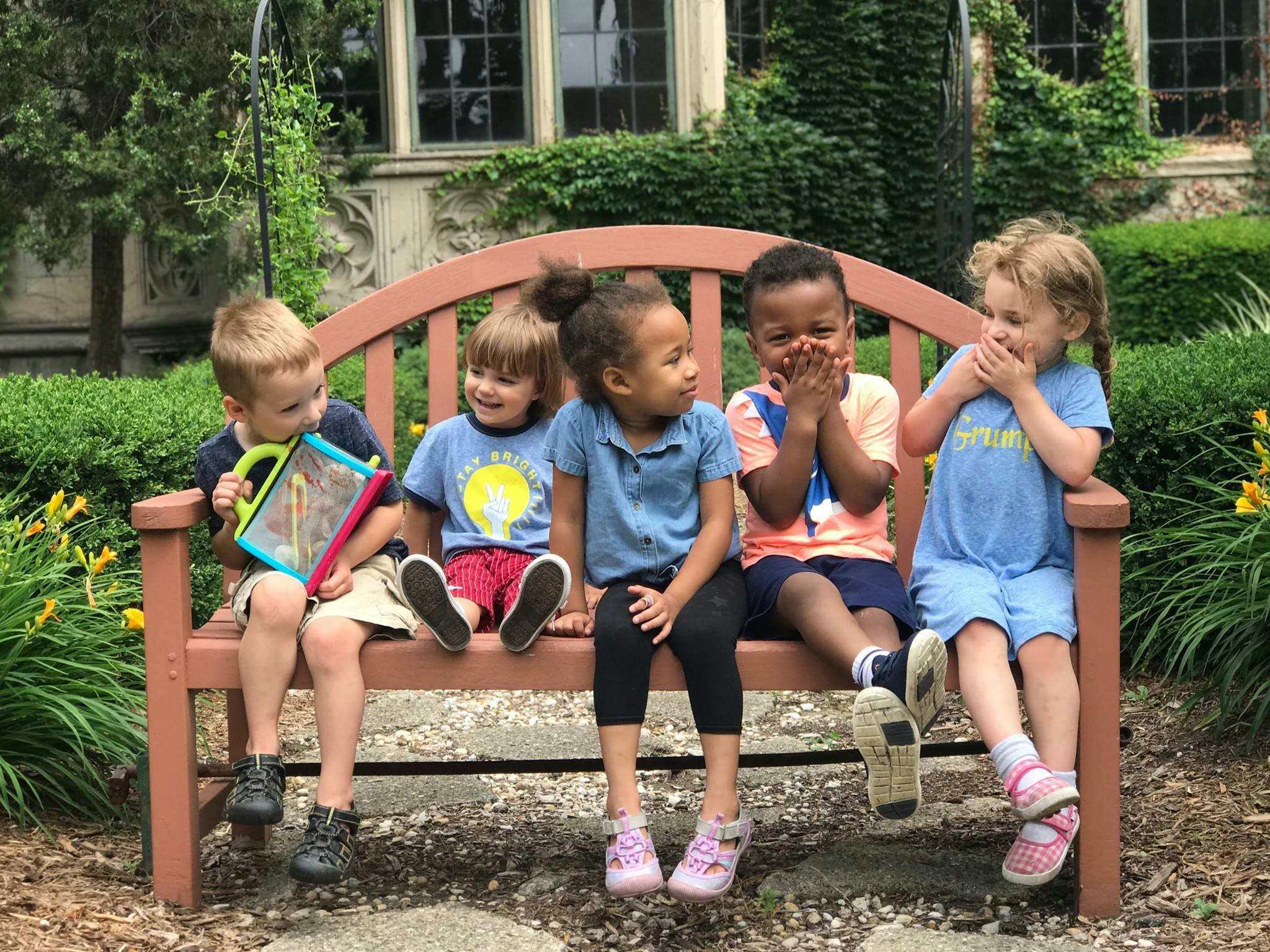 Five children sitting on a park bench