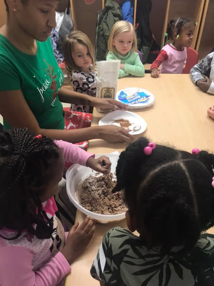 Adult and children at a table preparing food