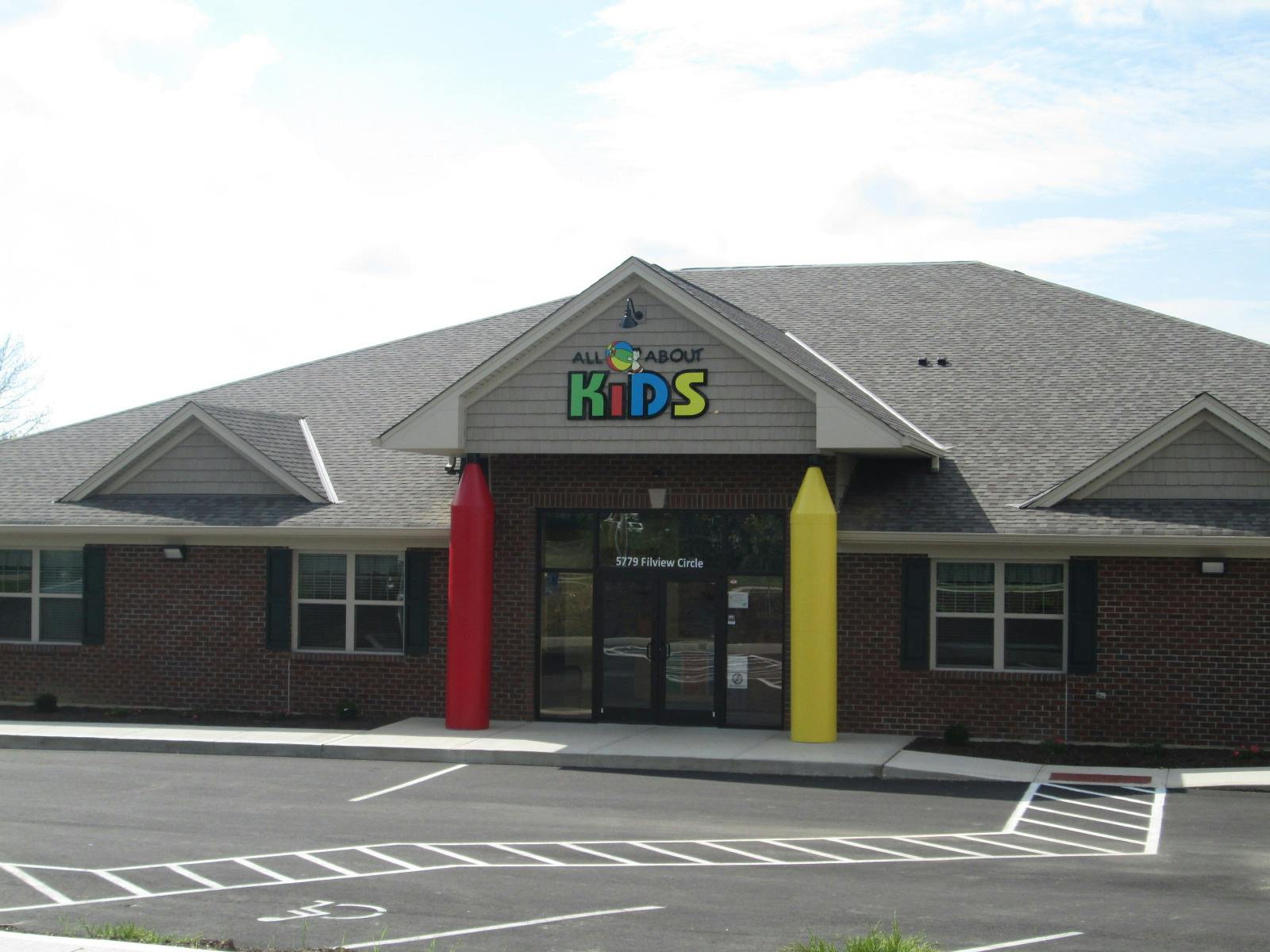 Building with "KIDS" sign and large red and yellow crayon decorations