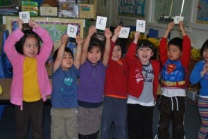 Children holding up cards with letters above their heads