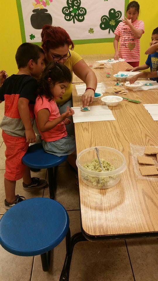 Adult and children decorating cookies at a table
