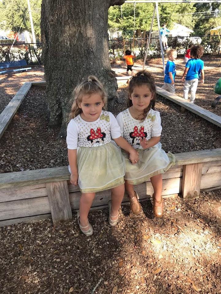 Two children sitting on a wooden border in a playground
