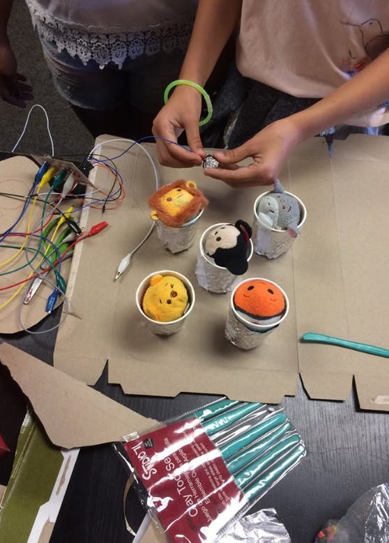 Person's hands working with small objects and wires on a table with crafts