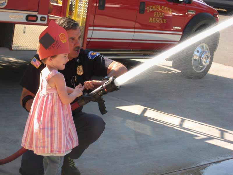 Adult and child holding a fire hose with water spraying out