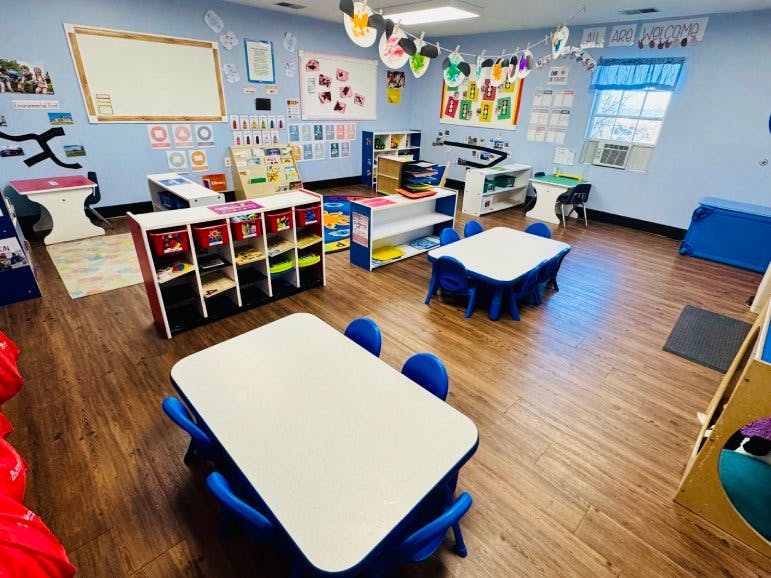 Classroom with blue walls, tables and chairs, and learning materials