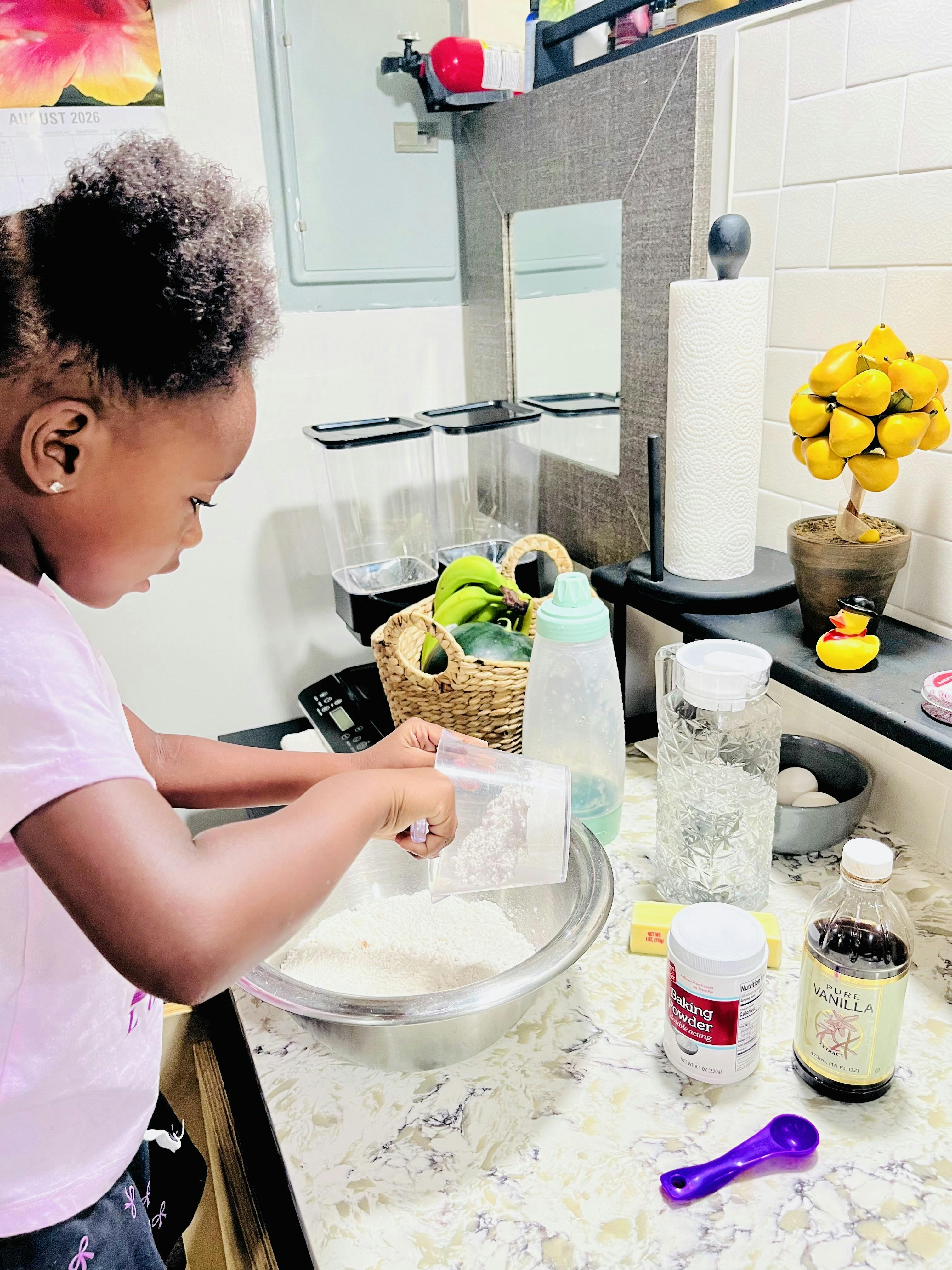 Child pouring baking powder into a bowl in a kitchen