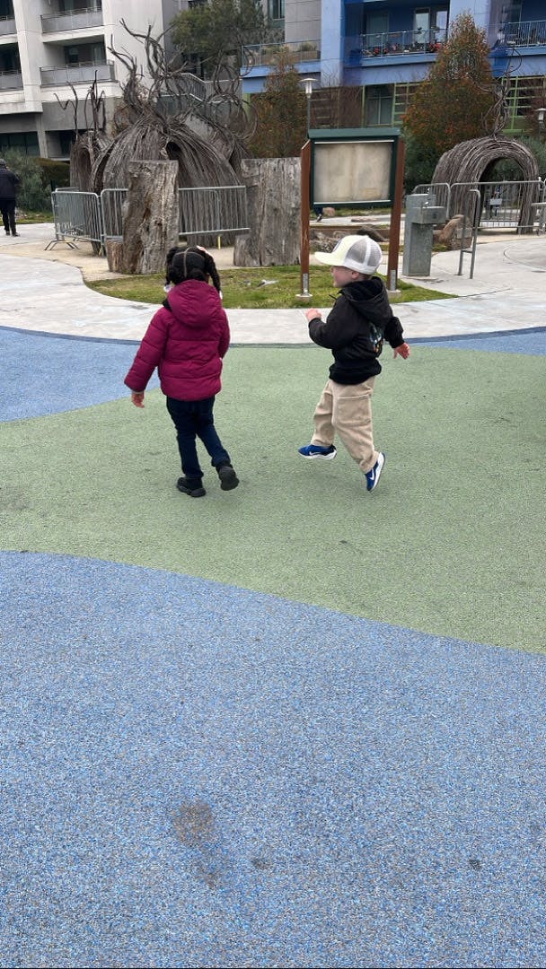 Two children walking on a playground surface